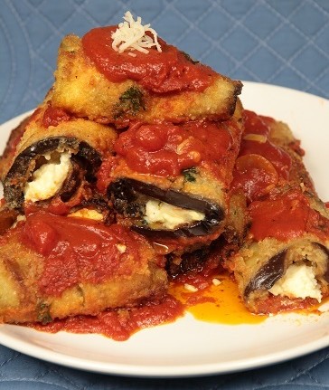 A plate of food with some eggplant and sauce