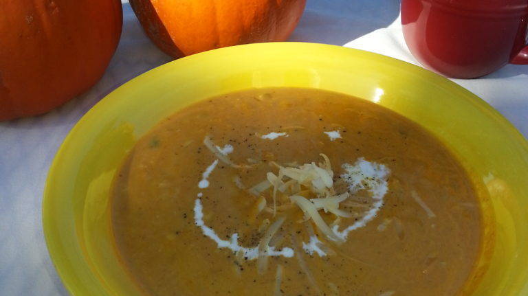 A bowl of soup on the table with pumpkins