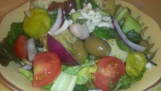 A plate of salad with dressing on the side.