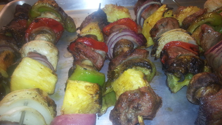 A grill with several different kabobs of food on it.