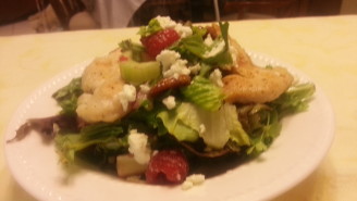 A salad with chicken, strawberries and feta cheese.