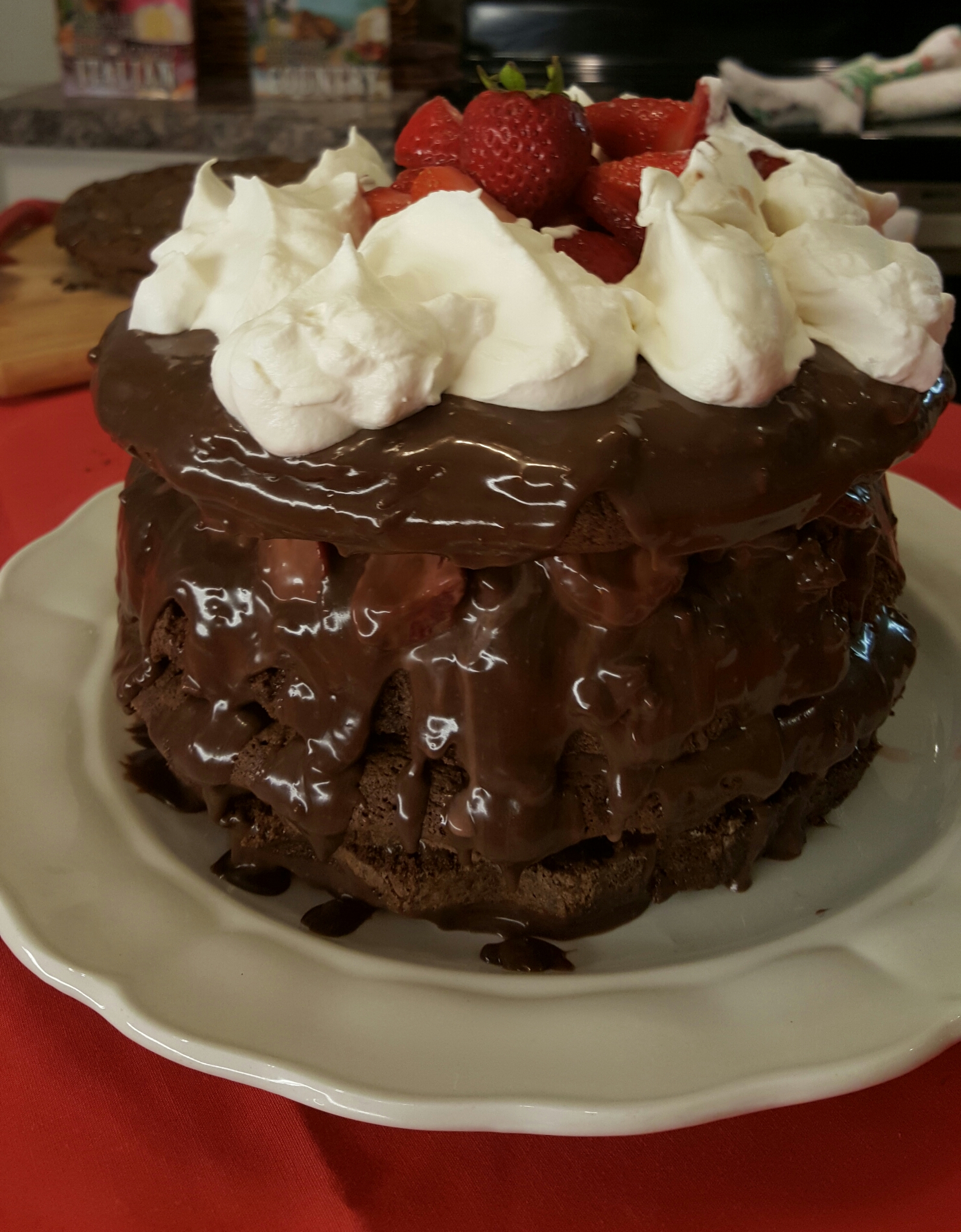 A chocolate cake with whipped cream and strawberries on top.