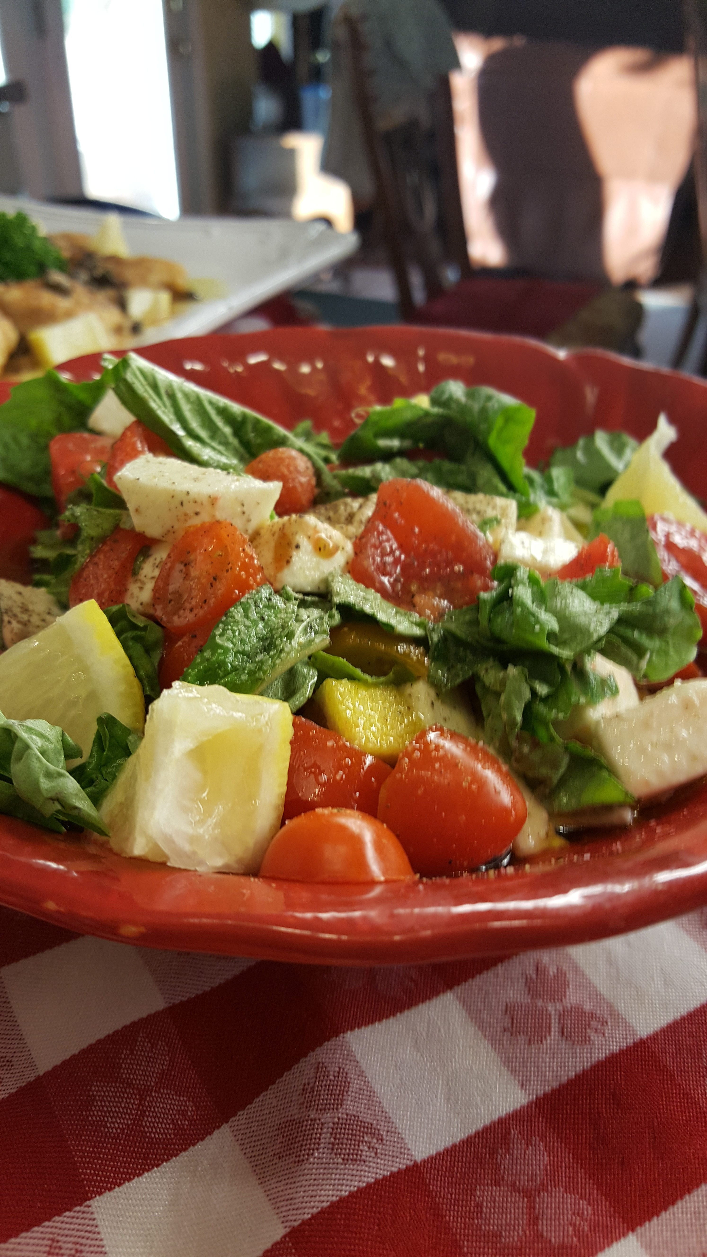 A red bowl of salad with tomatoes and lettuce.