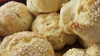 A pile of bread rolls covered in sesame seeds.