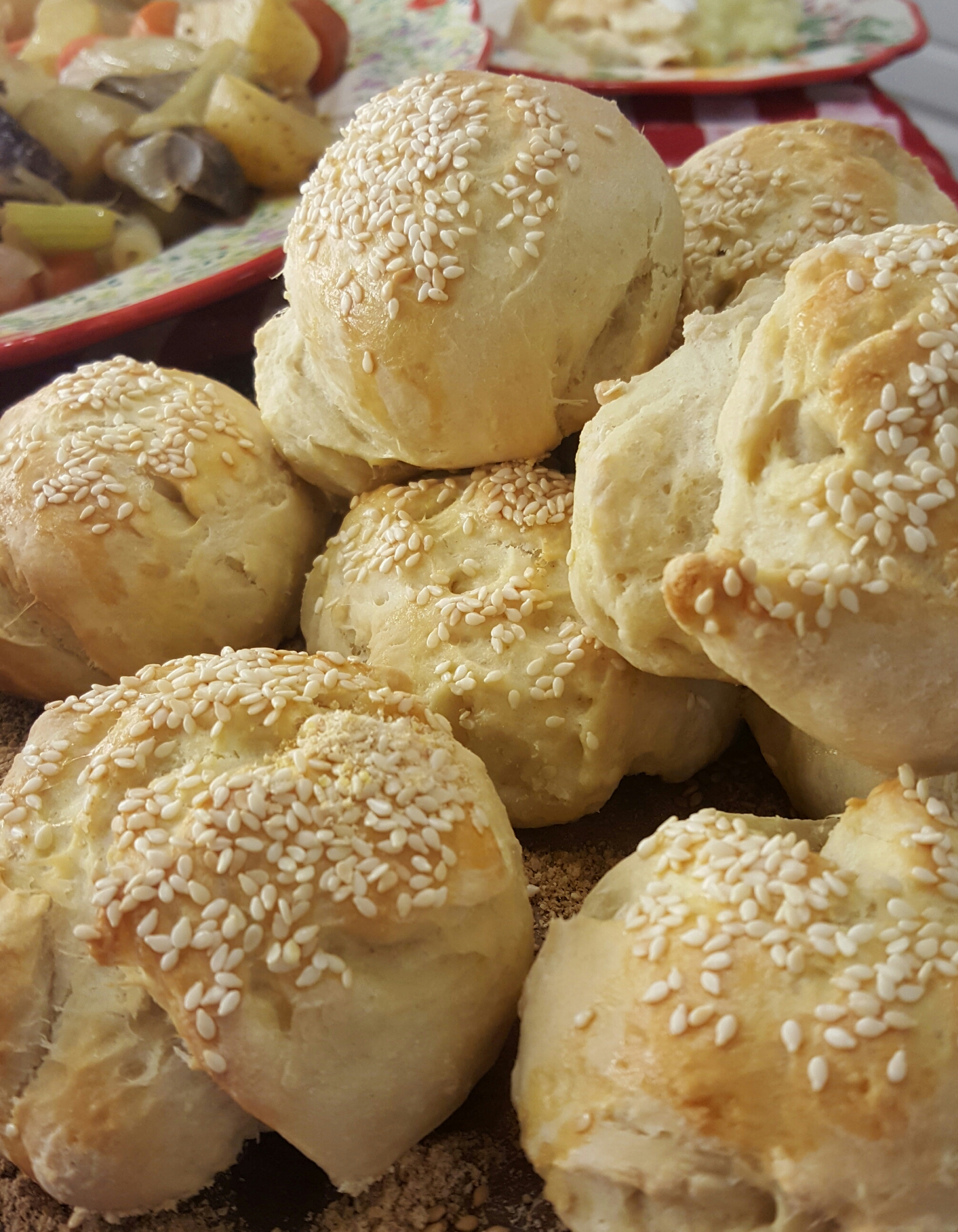 A pile of bread rolls covered in sesame seeds.