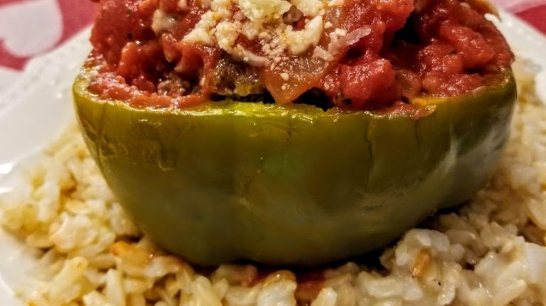 A stuffed pepper with rice on the side.