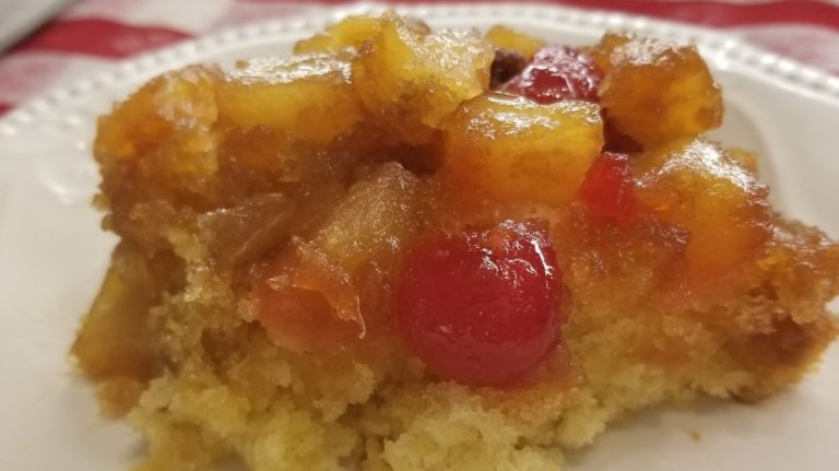 A piece of cake with pineapple and cherries on top.