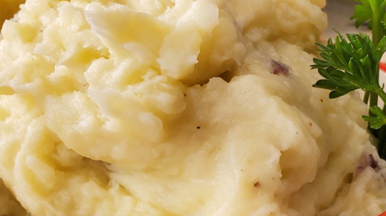 A bowl of mashed potatoes with parsley on top.