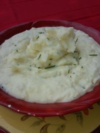 A bowl of mashed potatoes with chives on top.