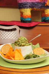 A bowl of guacamole and chips on the table.