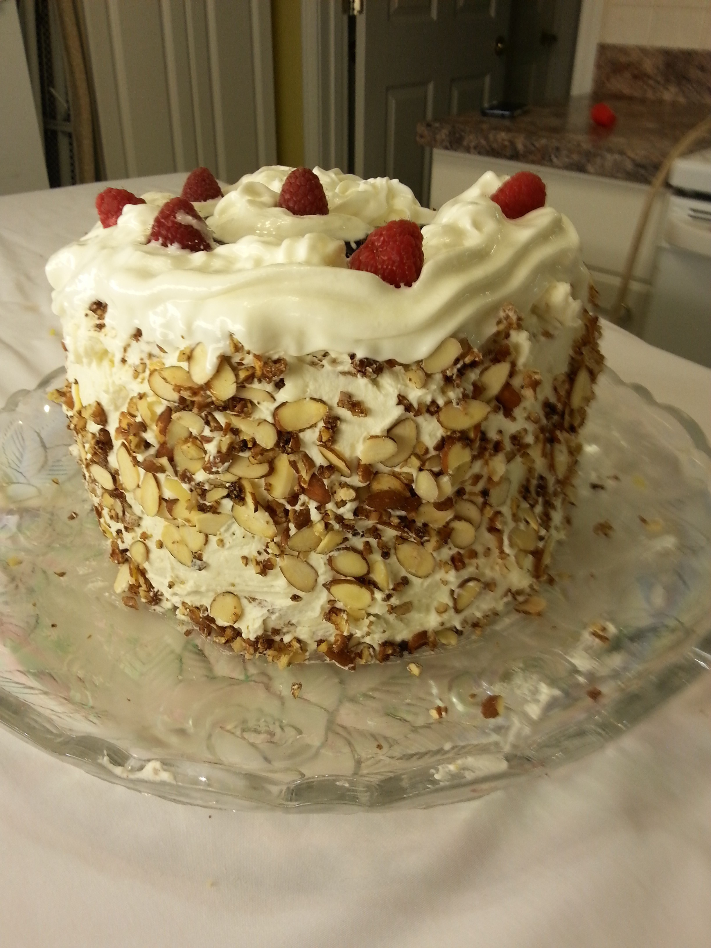 A cake with white frosting and nuts on top.