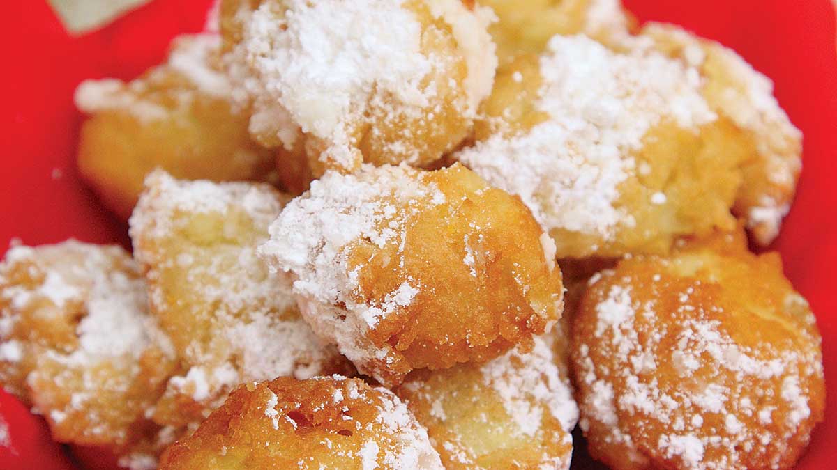 A close up of powdered donuts on a plate