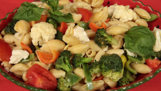 A bowl of pasta with broccoli, tomatoes and cauliflower.